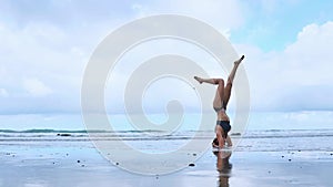 Flexible yoga woman stretching forward bend touching forehead to knees outdoors sunset sea beach close up. Professional