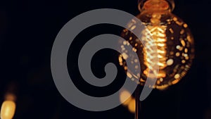 Flickering old fashion tungsten Edison light bulb lamp over black background. Slow motion shot 4K.