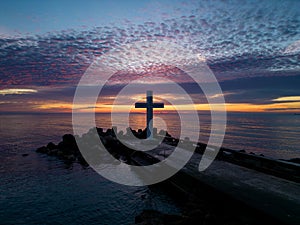 A flight around a Christian Holy cross early in the morning at sunrise. The large cross stands on the edge of a