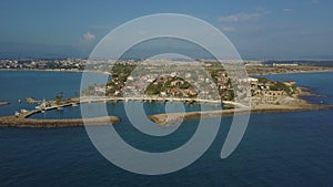 Flight around the peninsula with moored boats and low buildings. Dron flying away. Top view of the sea and the coast.