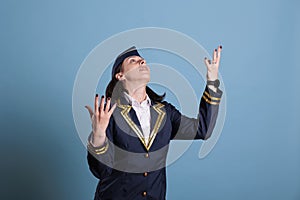 Flight attendant begging, looking upwards, raising hands to sky