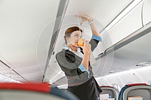 Flight attendant demonstrating how to use oxygen mask in airplane