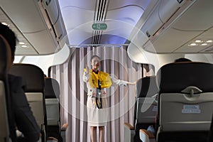 Flight attendant explaining safety regulations and showing the emergency exits to passengers on airplane cabin