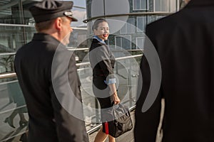 Flight attendant holding a bag and looking back at the pilots