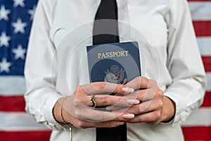 flight attendant holding fan of dollars and passport and standing against an flag background.