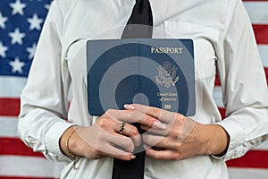 flight attendant holding fan of dollars and passport and standing against an flag background.