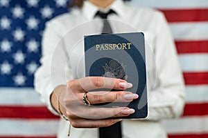 flight attendant holding fan of dollars and passport and standing against an flag background.