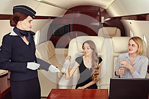 The flight attendant serves first class passengers inside the aircraft