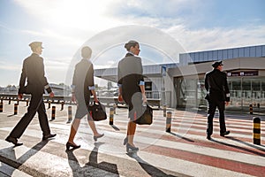 Flight attendants with bags and pilots crossing the road in the airport