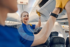 Flight attendants closing the overhead lockers in the passenger cabin