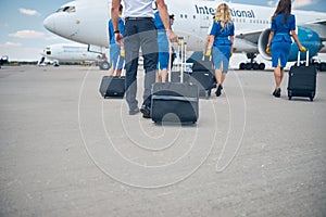 Flight attendants and pilots carrying trolley luggage bags at airport