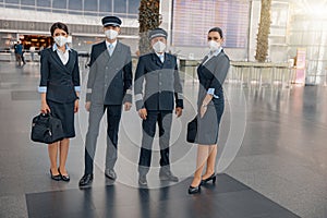 Flight attendants and pilots in protective face masks waiting for flight