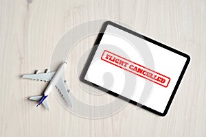 Flight cancellations concept. Top view airplane toy and digital tablet with message