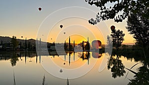 Flight of hot air balloons at dawn over a little lake in Umbria