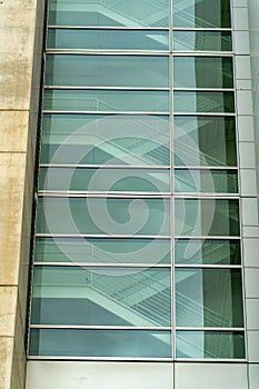 Flight of indoor stairs seen through decorative blue modern glass on side of building or mall in commercial districts