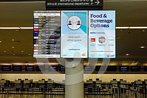 Flight information display service board in airport providing flight arrivals and departure times with covid messaging and