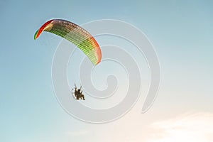 Flight on a motorized glider in the blue sky with bright backlight sunlight