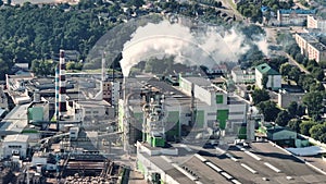 Flight near pipes with white smoke of woodworking enterprise plant sawmill. Air pollution concept on industrial landscape