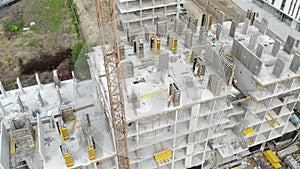 Flight near the unfinished monolithic house. Construction crane near the construction site. Top view of the construction