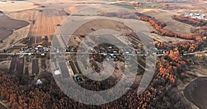 flight over and aerial panoramic view of village with houses, homestead, barns, greenhouses and gravel road at autumn