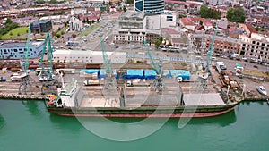 Flight over of the Batumi, Georgia. Bulk cargo ship under port crane, Batumi seaport, Georgia