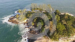 flight over beautiful tropical island. Waves crashing on rocks, sea green, on a sunny day.