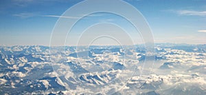 Flight over the clouds and snowy Alps on a sunny day