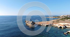 Flight over the coastline and rusty sunken ship EDRO III and clear sea with light waves