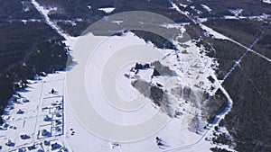 Flight over the countryside region on a winter cloudy day. Clip. Aerial view of a village on a snowy white field