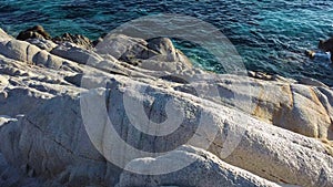 Flight over the massive white rocks on the sea coast and turquoise clear sea splashing. Aerial view