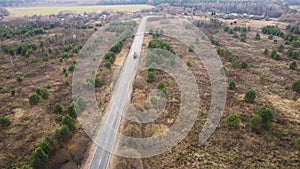 Flight over a narrow asphalt road with a passing truck outside the city.