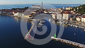 Flight over old city Piran, aerial panoramic view with old houses, St. George`s Parish Church, fortress, yachts, berths and sea.