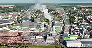 Flight over pipes with white smoke of woodworking enterprise plant sawmill. Air pollution concept on industrial landscape