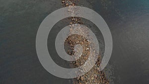 Flight over a rocky beach in the sea at dawn. Aerial shot