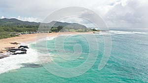 Flight over rocky coast of tropical island of Oahu Hawaii. View of Sandy Beach. Pacific Ocean Coastline. White clouds