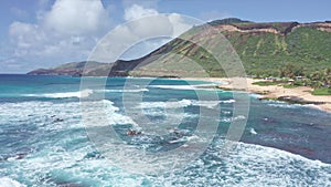 Flight over rocky coast of tropical island of Oahu Hawaii. View of Sandy Beach. Pacific Ocean Coastline. White clouds