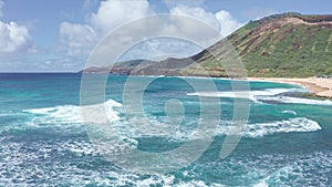 Flight over rocky coast of tropical island of Oahu Hawaii. View of Sandy Beach. Pacific Ocean Coastline. White clouds