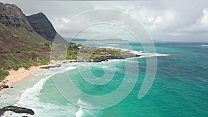 Flight over rocky coast of tropical island of Oahu Hawaii. View of Sandy Beach. Pacific Ocean Coastline. White clouds