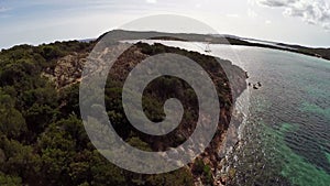 Flight over sea bay with rocks and yacht. Rondinara bay, Corsica, France. Aerial view.
