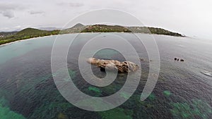 Flight over the sea with rocks and stones in water, Corsica, Santa Giulia beach. Aerial view.