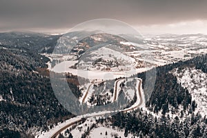 Flight over the winter mountains with mountain road serpentine