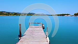 Flight over the wooden dock jetty towards blue lagoon with tranquil azure sea water. Summer vacation concept