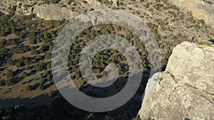 Flight over of young woman dancing on the top of a mountain above the sea. Lady on the summit in beautiful scenery.