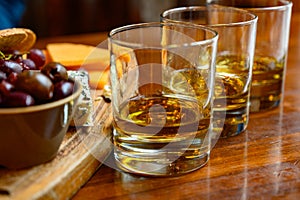 Flight of Scottish whisky, tasting glasses with variety of single malts or blended whiskey spirits on distillery tour in pub in photo