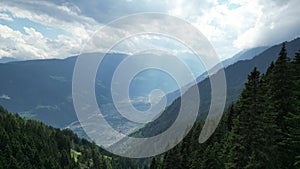 Flight through trees towards valley with village Partschins and mountain panorama in Texel group, South Tyrol, Italy