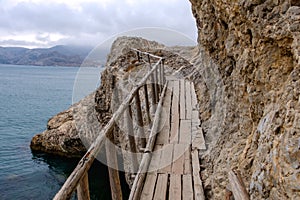 Flimsy old rotten bridge across the rocks on the sea coast