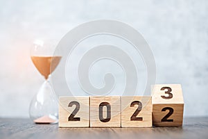 Flip block 2022 to 2023 text with hourglass on table. Resolution, time, plan, goal, motivation, reboot, countdown  and New Year