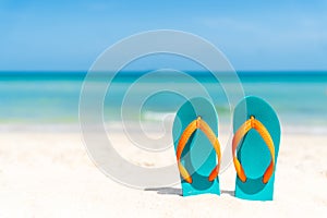 Flip flop on sandy beach, green sea and blue sky background photo