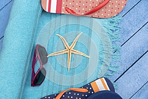 Flip-flops, beach towel and sunglasses on wooden table.