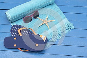 Flip-flops,beach towel and sunglasses on wooden table.